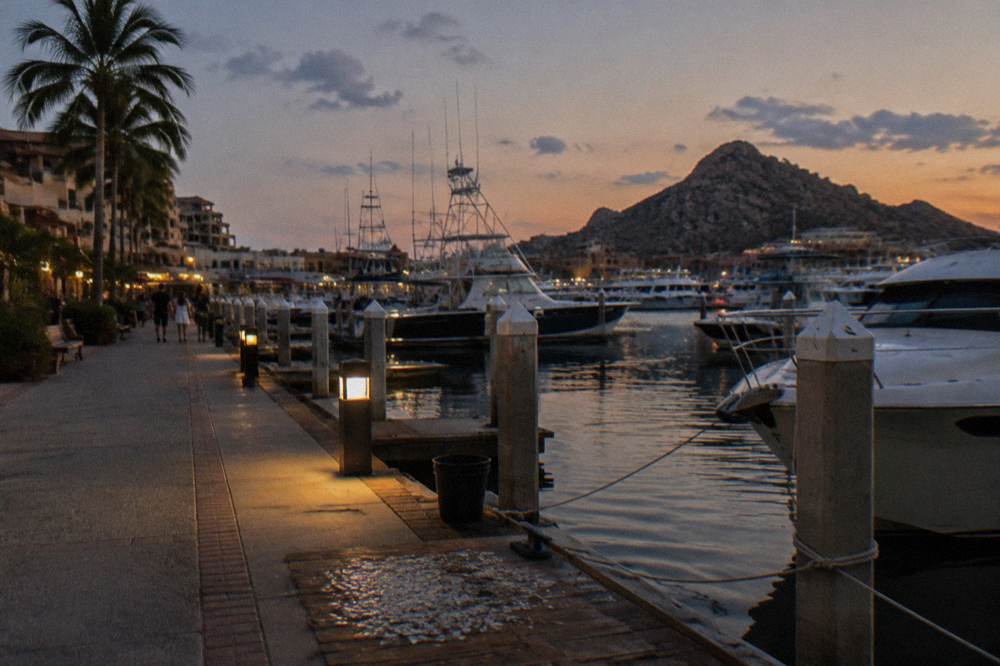 The Cabo San Lucas marina boardwalk with boats moored at dusk