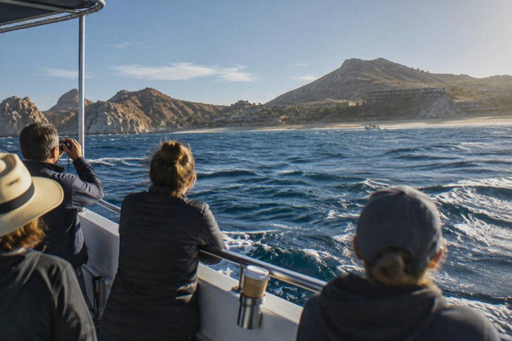 A small tour boat on open water with passengers watching the horizon