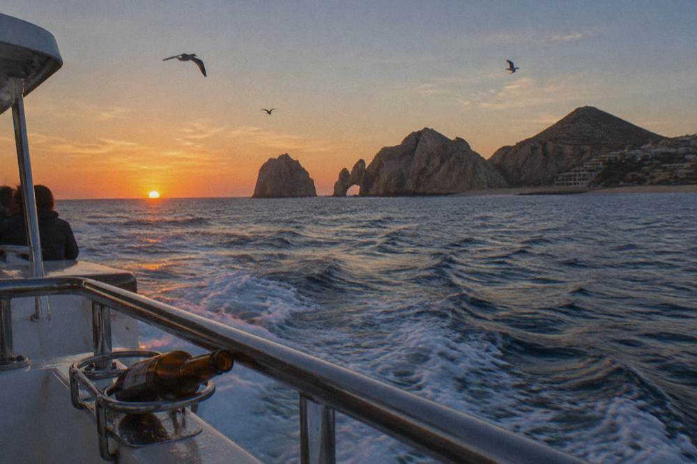 A wide horizon with the sun low over open ocean seen from the deck of a boat