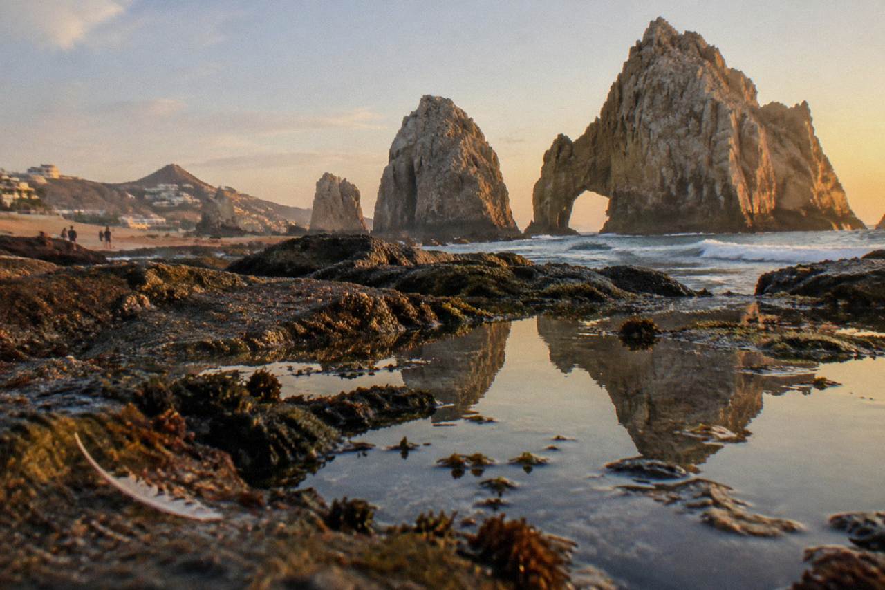 Golden evening light on rock formations at the tip of the Baja peninsula above calm water