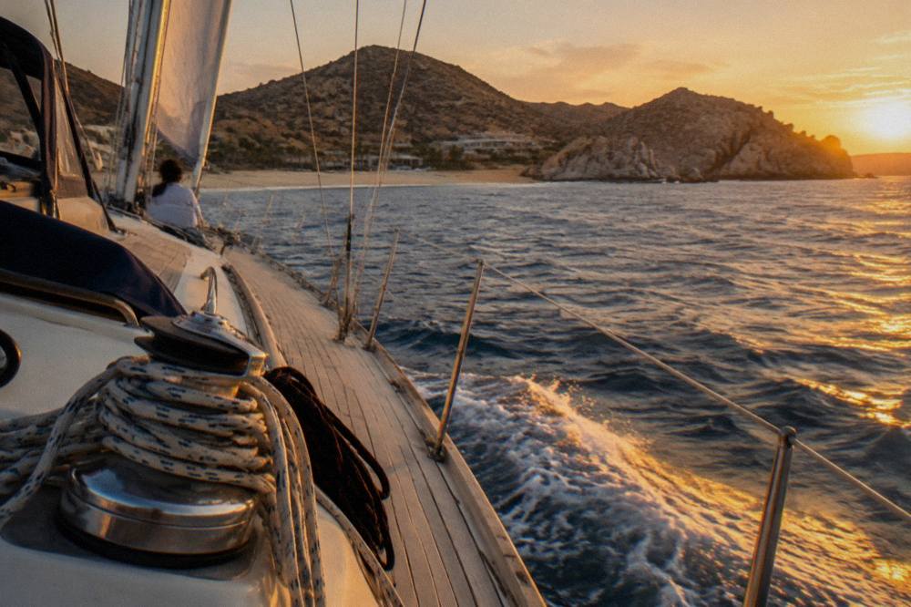 Sailing yacht under sail in open water near Cabo San Lucas at golden hour