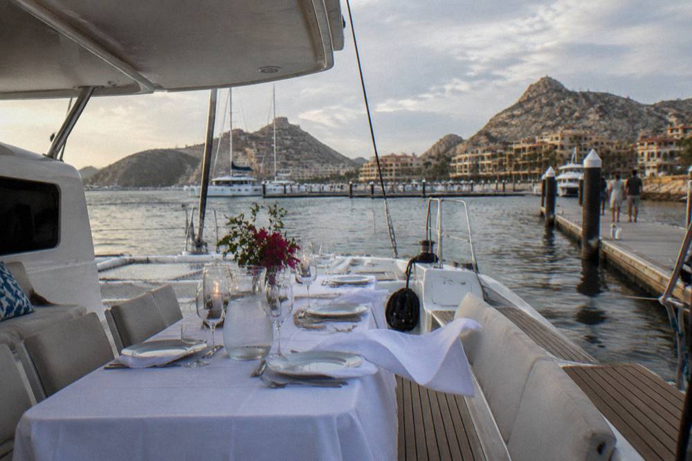 Catamaran deck with seating and tables set for an evening dinner cruise