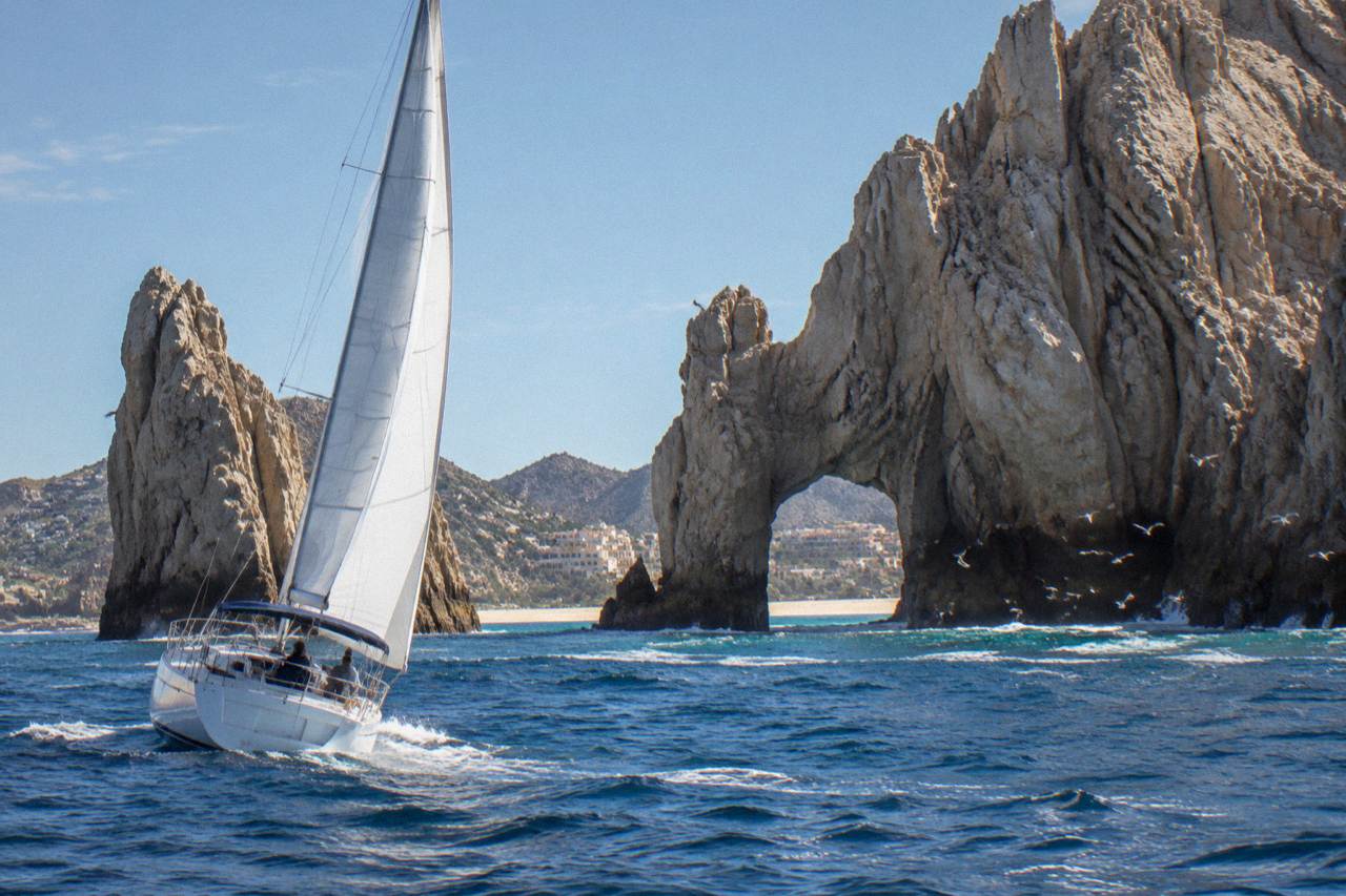 Sailboat under warm light near rock formations at the end of the Cabo San Lucas bay