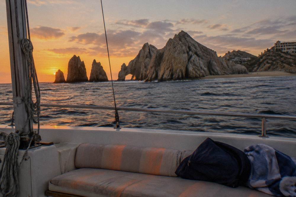 Folded jacket and towel on a bench seat aboard a boat under an orange evening sky