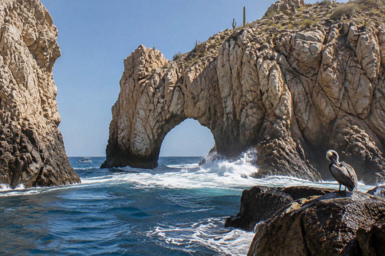 Golden granite arch rising from the sea at the tip of a rocky point