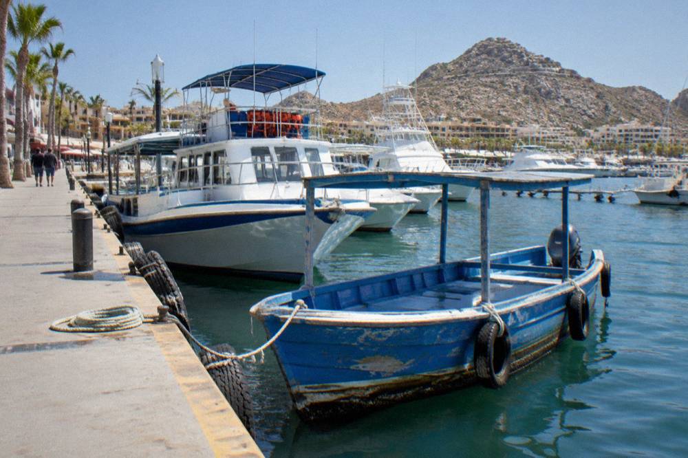 Wooden water taxi boat docked at a marina slip beside tour boats in Cabo San Lucas