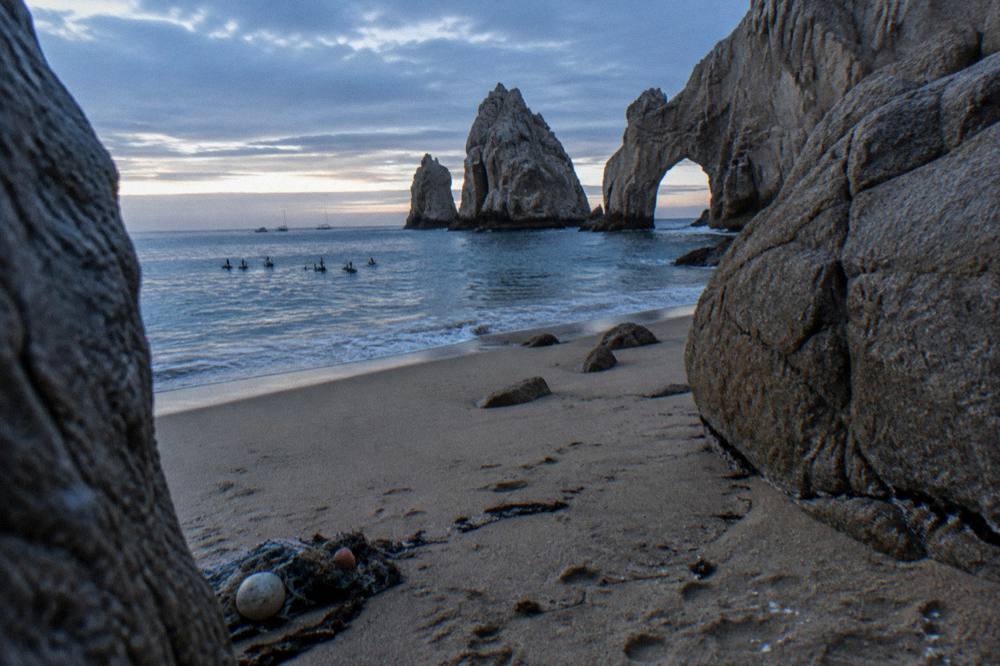 Empty stretch of pale sand between granite boulders at Lover's Beach near the Arch