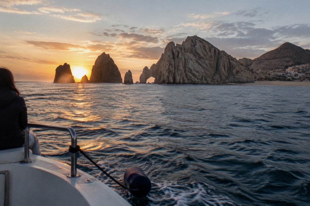 Sunset over calm water near rock formations at the end of the Cabo San Lucas bay