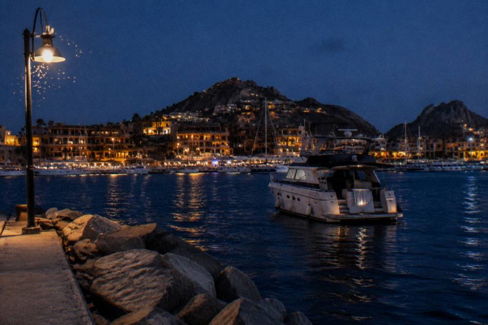 Private yacht anchored near the Cabo San Lucas marina with the town lights behind it
