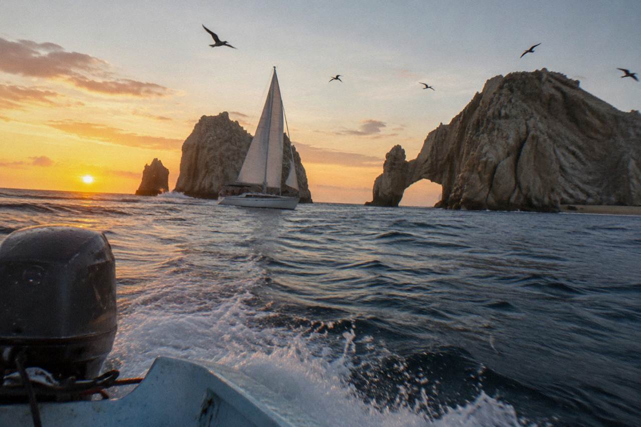 Sailboat passing the rock arch at Land's End near Cabo San Lucas at sunset