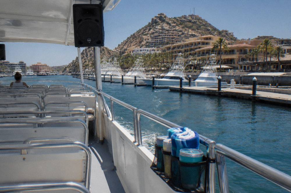 Open deck of a party cruise boat with music speakers and seating as the boat leaves a marina