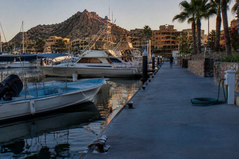 Marina dock in Cabo San Lucas in late afternoon with boats moored and golden light on the water