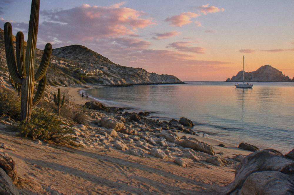 Sunset over the Cabo San Lucas coastline with calm ocean and scattered clouds