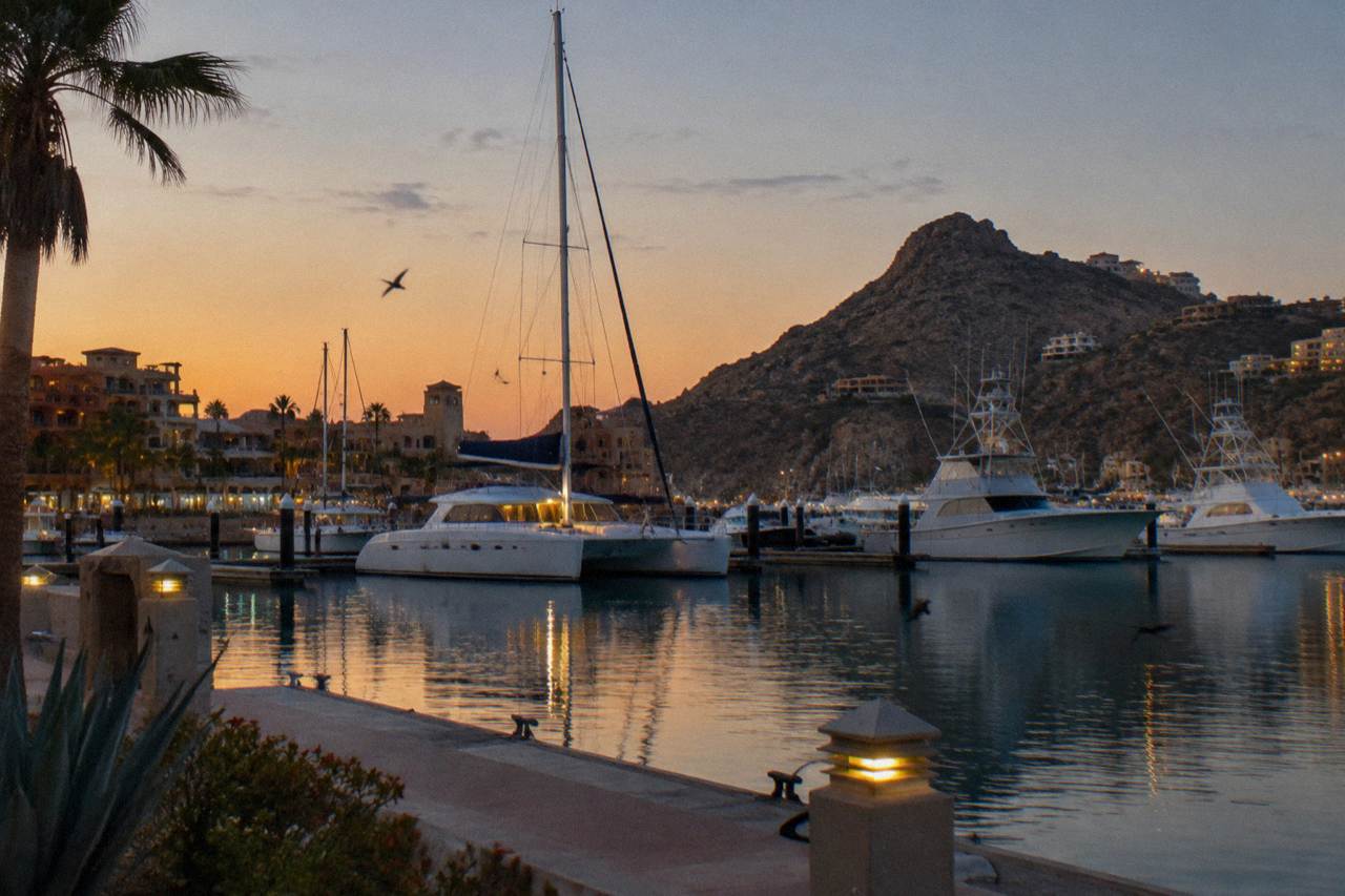 Calm marina water in Cabo San Lucas with boats at their docks under a clear evening sky