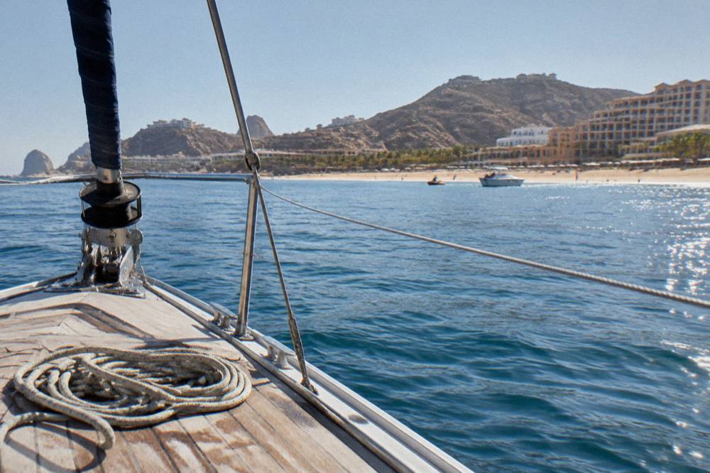 Bow of a luxury sailing yacht with rigging against a calm sea horizon near Cabo San Lucas