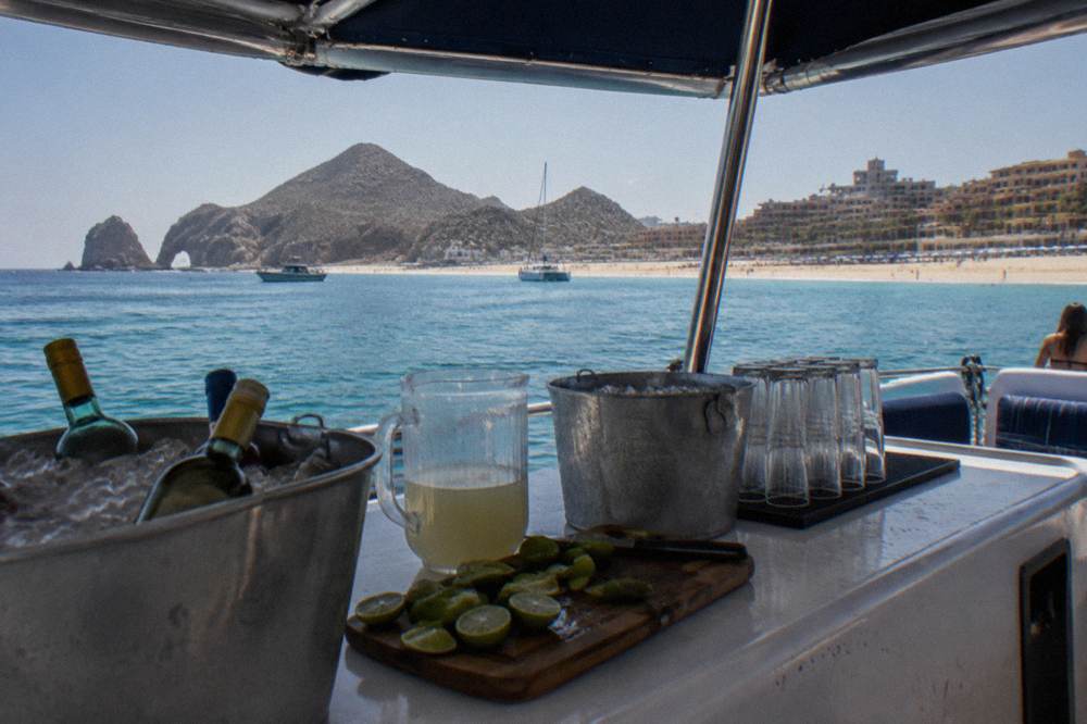 A shaded catamaran deck with seating and a serving area set for drinks