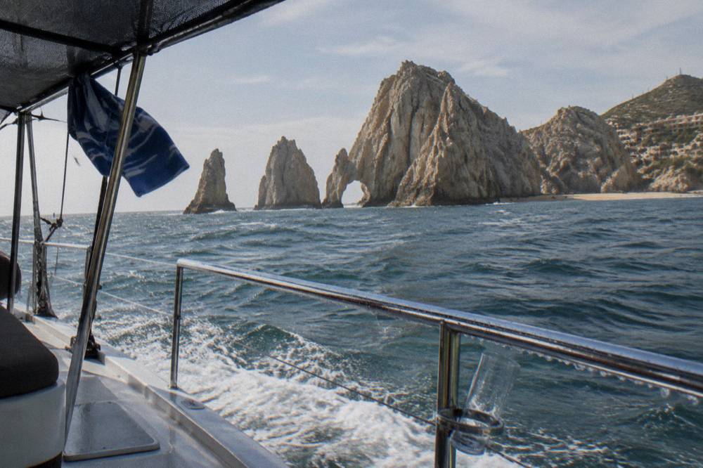 A catamaran deck with a shaded seating area and open water beyond the railing