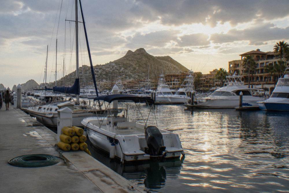 Boats of several sizes moored along the Cabo San Lucas marina boardwalk in late afternoon