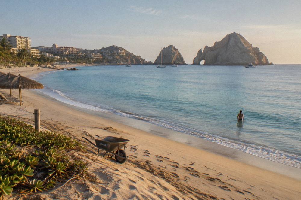 Wide sandy stretch of Medano Beach with calm turquoise water and distant rock formations