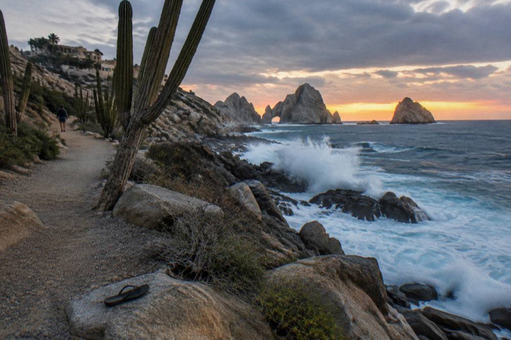 Rocky shoreline path along the Pacific side of the peninsula at dusk with waves on the rocks