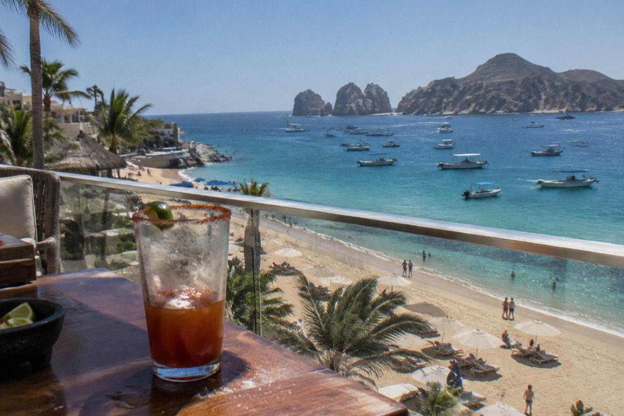 Wide sandy beach with calm turquoise water and boats anchored offshore at the tip of the Baja peninsula
