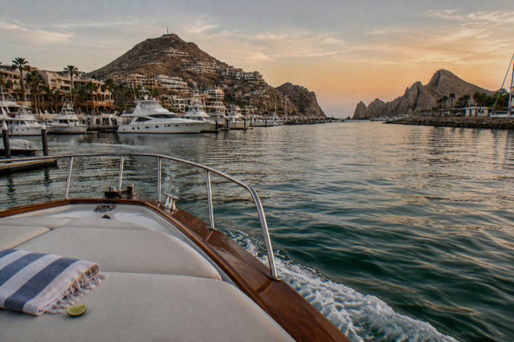 Bow of a private yacht underway near Cabo San Lucas with calm water and dusk sky