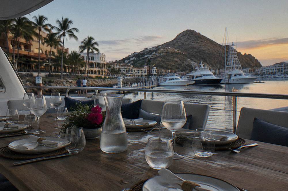 Dinner table set on the deck of a yacht with plates and glasses in evening light