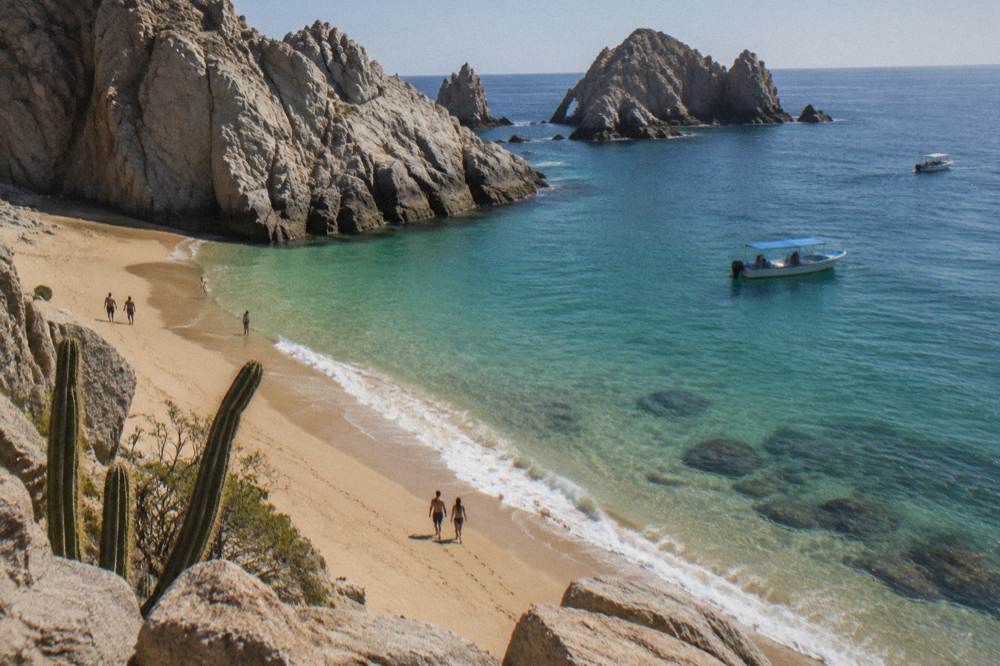 A small sandy cove between granite rock formations with calm clear water