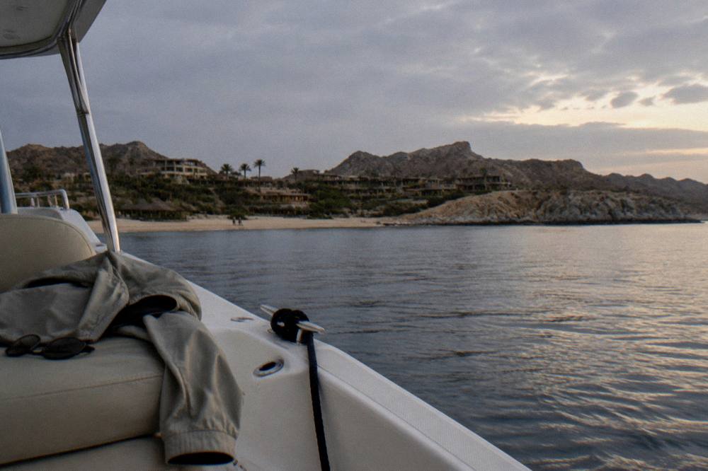 A folded light jacket and sunglasses resting on a boat seat at dusk