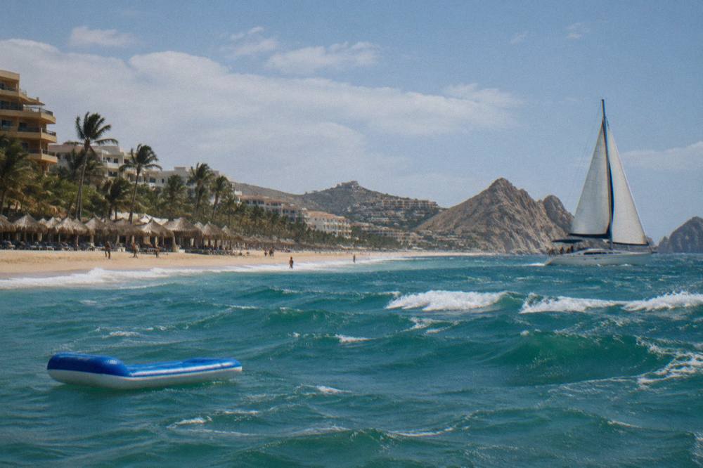 Sailboat under way near the Cabo San Lucas shoreline in late afternoon light