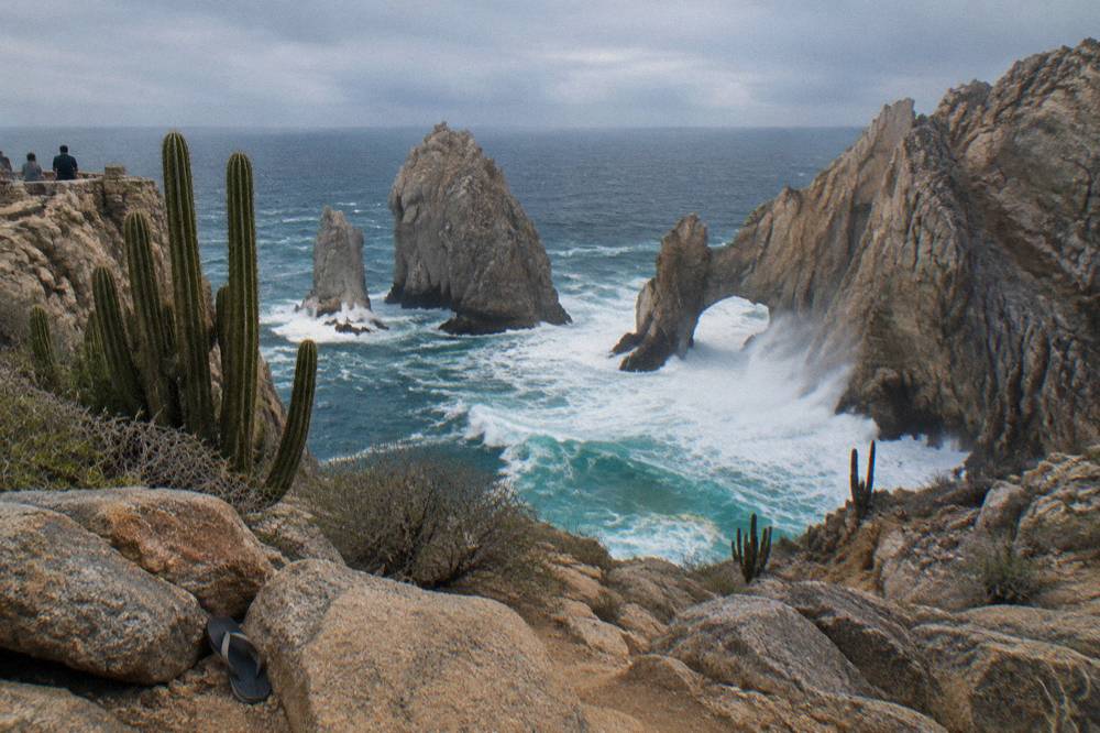 Towering rock arch at Land's End with waves breaking against the cliff base