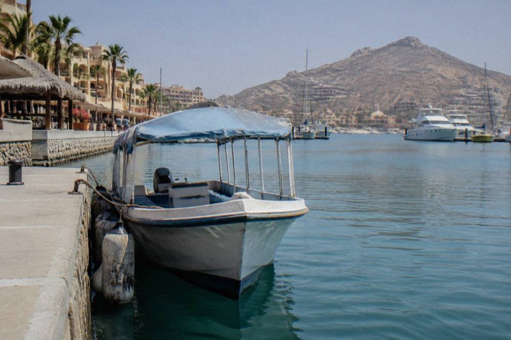 Water taxi boat near a marina dock with rocky headland in the background