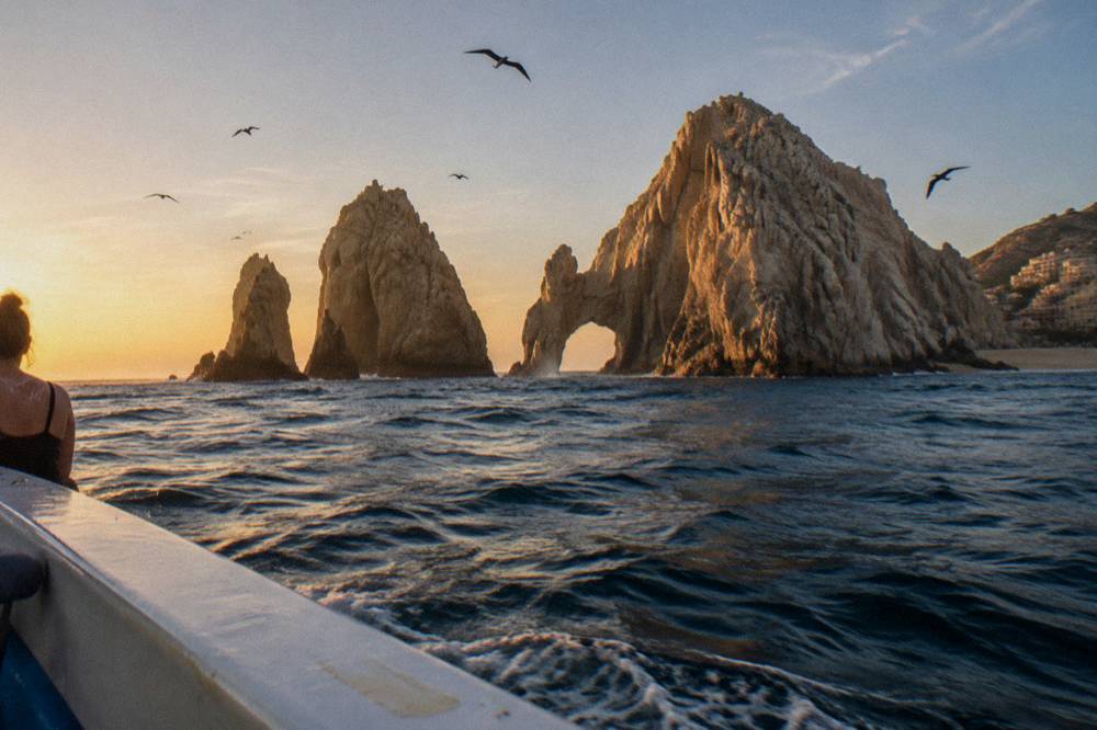 Warm evening light on rock formations at the end of a peninsula seen from open water