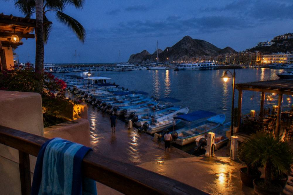 Fishing and tour boats moored in a marina at dusk with restaurants along the shore