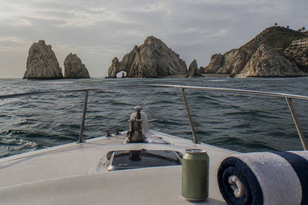 A calm horizon seen from the center of a boat deck with a rocky coastline far off